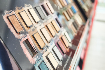 Shelf with samples of multi-colored eyeshadows in a cosmetic store