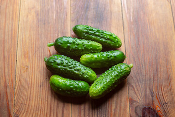 Ripe fresh healthy diet vegetarian food with vitamins. Green cucumbers lie on a wooden surface. Harvesting season.