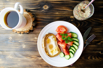 breakfast with toast with egg, vegetables, porridge and coffee top view on wooden background