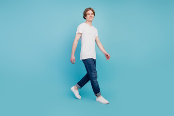Full body photo of cheerful positive guy go isolated over blue background