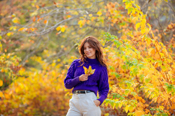 a young woman in an autumn park in a purple sweater