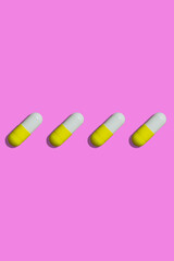 yellow and white pills on a pink background top view. pills pattern