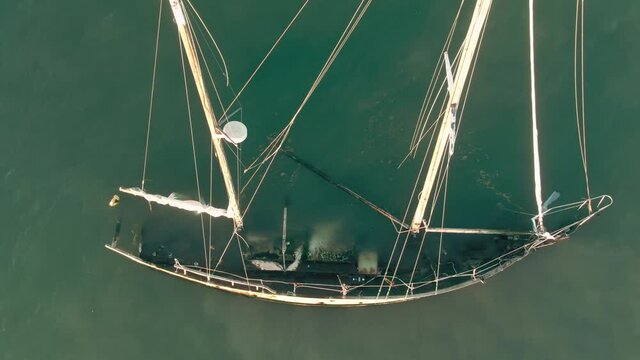 Aerial: Sunken yacht in the water at sunset. San Pablo Bay, Oakland, USA