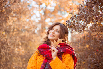 a young woman in an autumn park in an orange sweater