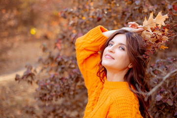 a young woman in an autumn park in an orange sweater