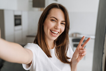 Young white woman smiling and gesturing while taking selfie photo