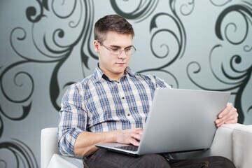 Smiling young adult freelance business man using laptop