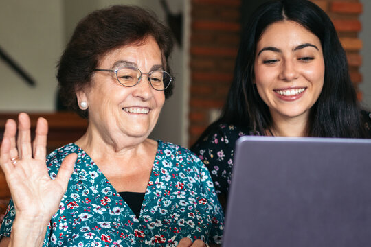 Smiling grandmother with granddaughter having video chat on laptop