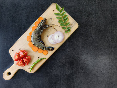 Fresh Giant Tiger Prawn decorated with herbs and vegetables on a wooden pad.Selective focus.Space for text.
