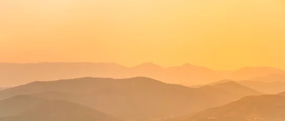Poster Silhouettes of mountains at dawn or sunset. Beautiful natural orange landscape © KseniaJoyg