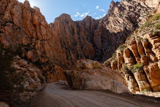 Gravel road of Swartberg pass winding through contorted rock formations