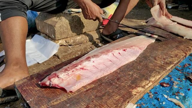 The seller cuts the fish fillet into steaks. An ordinary fish market on the Indian coast.
