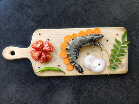 Fresh Giant Tiger Prawn decorated with herbs and vegetables on a wooden pad.Selective focus.