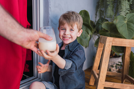 Crop father passing glass of milk to smiling son