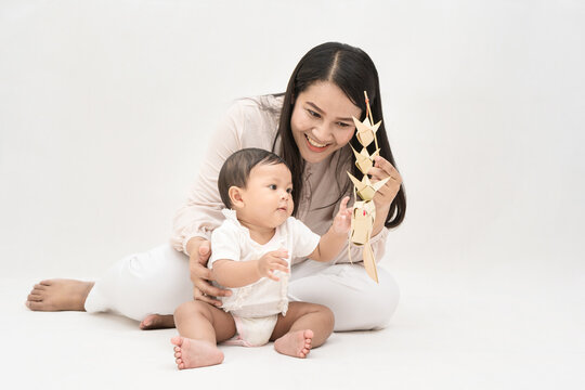 Asia mother plays with her baby girl with weave fish on white background.