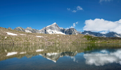 Rocky mountain reflecting in an mountain lake at a sunny day near Furka Pass. Uri Alps, Switzerland, Europe
