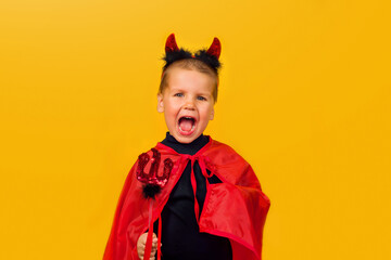 One little toddler boy in a carnival costume for Halloween is isolated on a yellow background. Traditions, holidays concept.