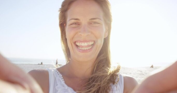 beautiful woman taking selfie using phone on beach at sunset smiling and spinning on vacation