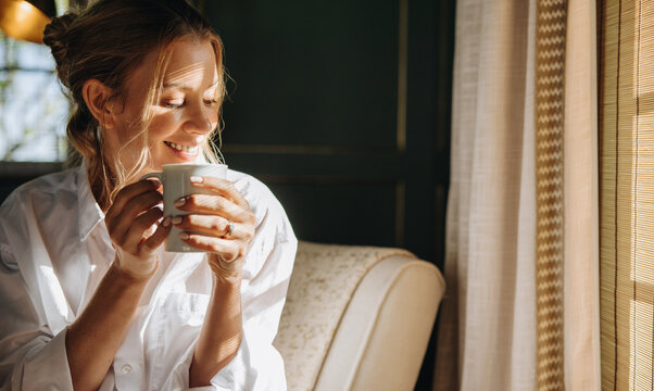 Smiling young woman enjoying a cup of coffee in a hotel