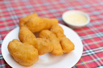 deep-fried doughsticks and sauces and dips in plastic plates laid out on a gridded table.