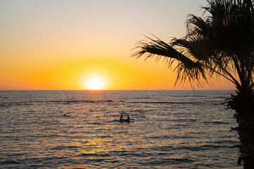 Two girls sit on sup board in the quiet mediterranean sea at sunset in the city of paphos in...