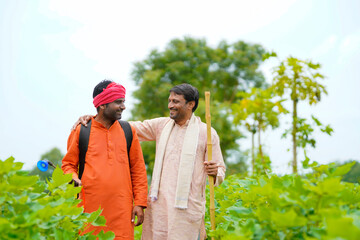 Two indian farmers working and discuss at green cotton field.