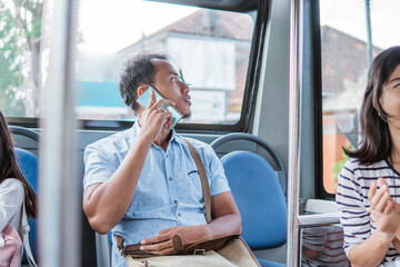 male asian using mobile phone while riding public bus or metro