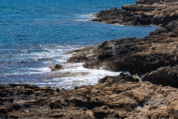 Rocky coast and waves of the Mediterranean Sea off coast of Cyprus near the city of Paphos in summer in good weather. Wet stones near mediterranean sea. Amazing nature seascape with rocky seacoast