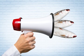 Human hand holding megaphone with fish. Contemporary art collage, modern artwork.