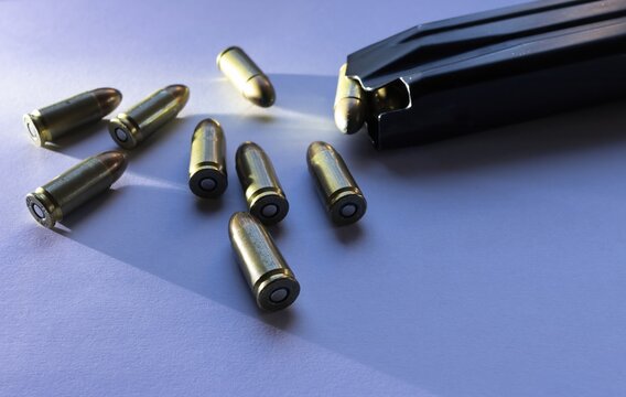 9mm caliber parabellum bullets isolated with grazing light next to a magazine of pistol ammunition