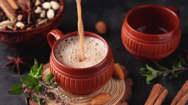 Pouring Indian Masala Chai traditional beverage tea with milk spices Kerala India Sri Lanka 4K video footage. Two cups organic tulsi tea ayurvedic herbal drink good for winter immunity boosting.