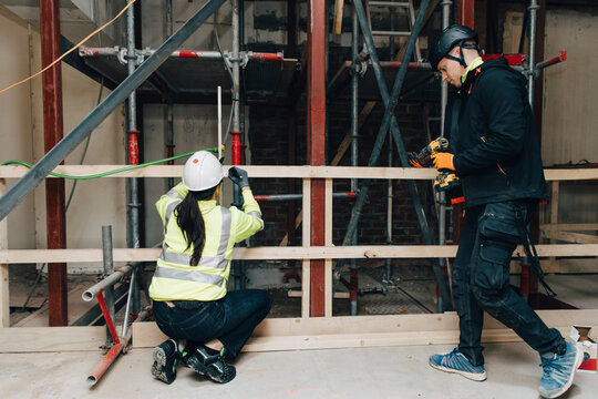 Full length of male and female worker together at construction site