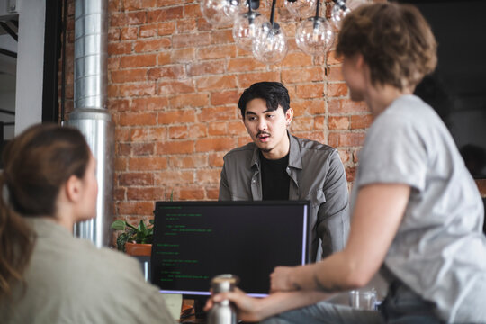 Male computer programmer discussing with female colleagues in office
