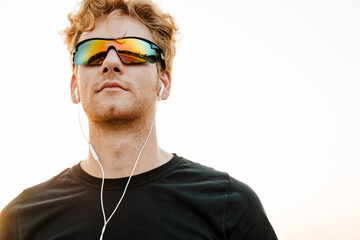 Young sportsman listening music with earphones while working out