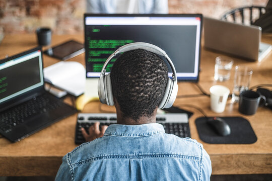 Rear view of male programmer working on computer at startup company
