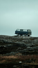 Fototapeta na wymiar A hippy car stands on the edge of the rocks against the backdrop of a cloudy sky