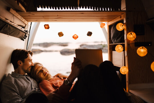Male friends using laptop in camping van at evening