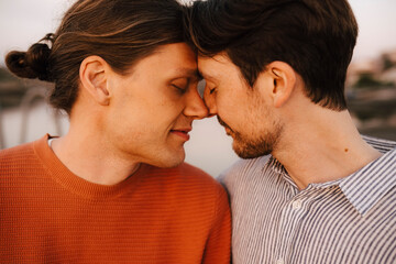 Romantic male friends touching forehead at evening