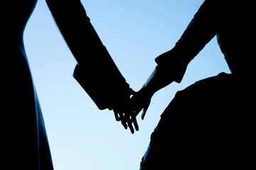 silhouettes of the bride and groom.  Young couple holding hands each other . Rear view couple at...