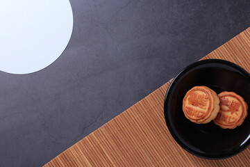 Chinese moon cake on a dark gray and bamboo background. Asian traditional mid-autumn festival. Translation of hieroglyphs: mango, pomegranate and lotus.