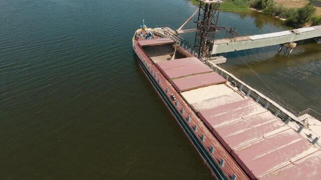 grain loading terminal. agriculture a transportation business concept. grain barge boat tugboat. loading grain on water into a barge boat. agriculture food transportation elevator business.