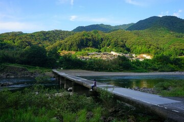Woman sitting on Nagaoi Sinking bridge over Shimanto River Valley in Kochi, Shikoku, Japan - 日本 四国 高知 四万十川 長生沈下橋に座る女性
