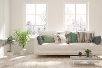 Fototapeta premium White living room with sofa and winter landscape in window. Scandinavian interior design. 3D illustration