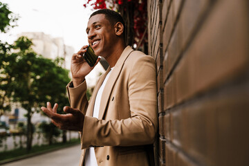 Young black man talking on mobile phone while standing at city street
