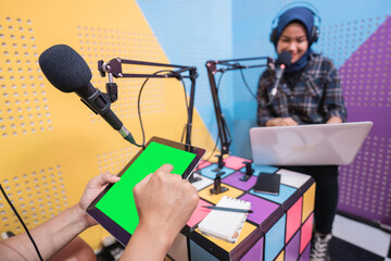 muslim asian woman and man talking on podcast studio together