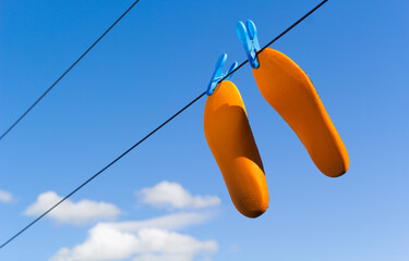 Orange footwear insoles drying on clothes or laundry line - obrazy, fototapety, plakaty