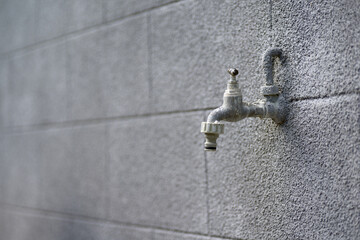 Back yard outdoor tap against grey painted wall.