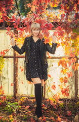 Woman with bob haircut in a black leather jacket and high jackboots is standing in an abandoned greenhouse in autumn