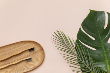 Bamboo toothbrush on a table with copy space on a white background. Styled composition of flat lay with tropical leaves.