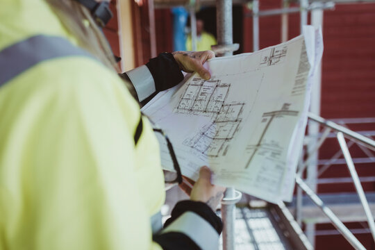 Female building contractor reading floor plan at construction site